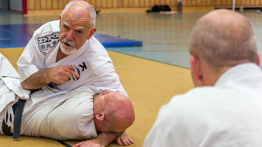 Patrick McCarthy demonstriert eine Karate Haltetechnik auf dem Boden.